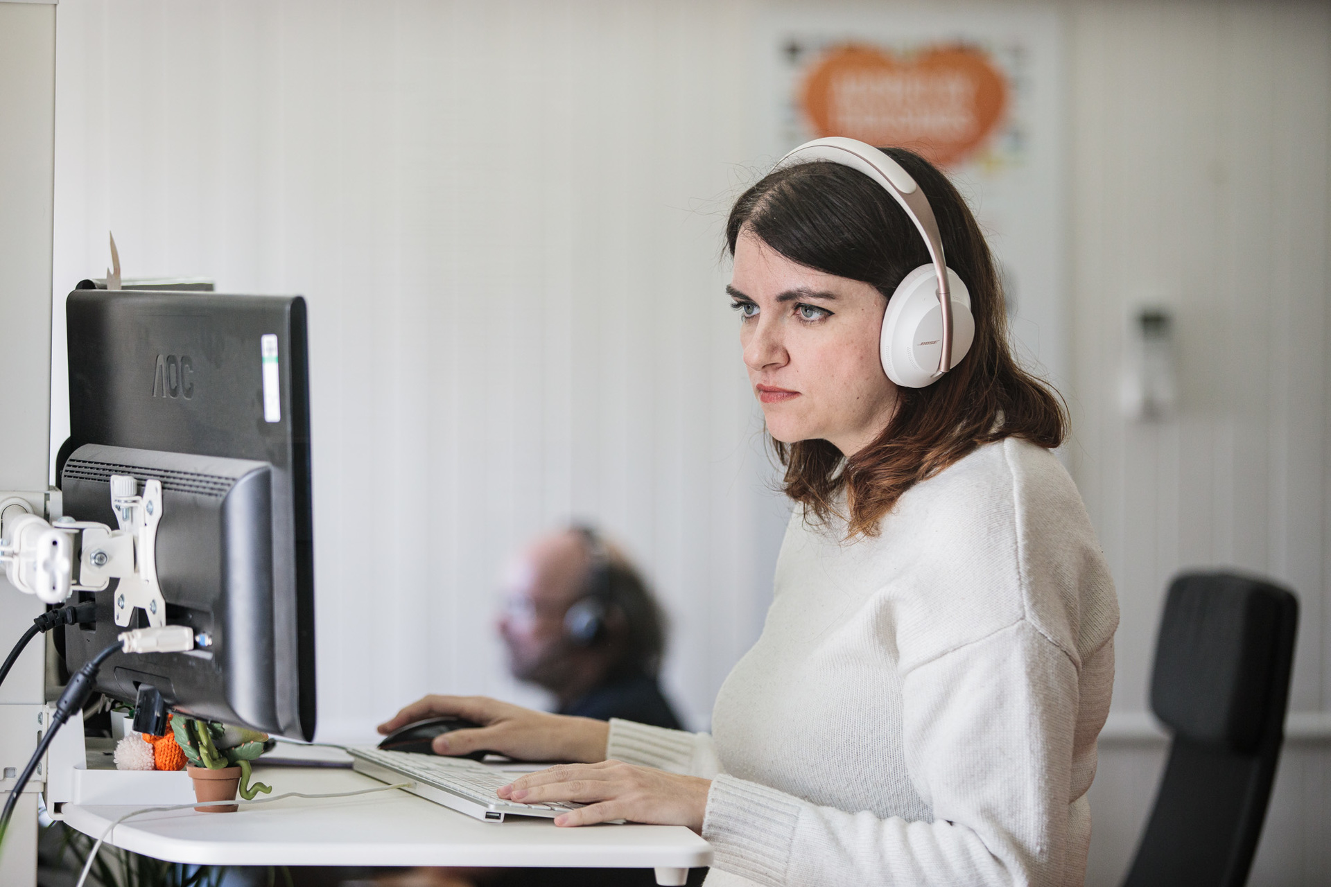 A woman stood up at her desk, with headphones on